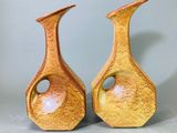 une paire de vases jaunes percés de trous, posés sur une table