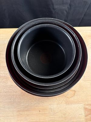 une pile de trois bols noirs posée sur une table en bois