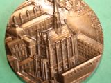 a silver medal with a picture of a city on it