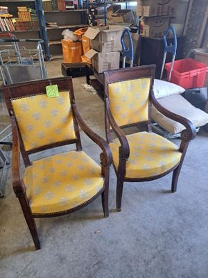 une paire de fauteuils rembourrés jaunes dans une pièce où se trouve une étagère remplie de livres