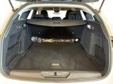 the back of a white car with a surfboard in it ' s trunk