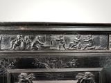 a silver metal fireplace with carvings on it