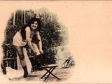 une vieille photo d'une femme debout à côté d'une chaise