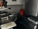 a kitchen with a stove, sink, and trash can in it