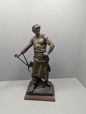 statue en bronze représentant un homme muni d'une canne et coiffé d'un chapeau, posée sur un socle en marbre