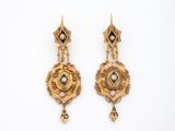 une image d'une paire de boucles d'oreilles en or sur fond blanc
