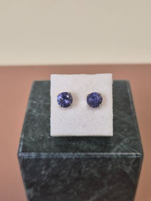 a pair of tanzane sapphire earrings on a marble block