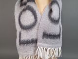 écharpe grise et blanche à motifs circulaires et à franges, posée sur une tête de mannequin