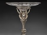 une assiette en argent posée sur un socle, sur laquelle est représenté un oiseau