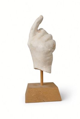 statue of a hand with a thumb up on a wooden base