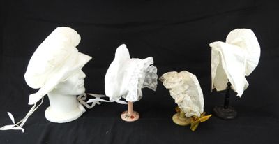 trois chapeaux blancs et un porte-chapeaux sur fond noir