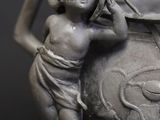 a statue of a boy holding a pot on a table
