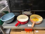 Plusieurs bols et casseroles sont posés sur une étagère dans un magasin.