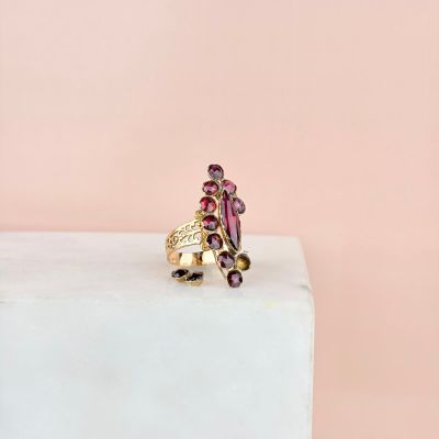 une bague en or sertie de grenats, posée sur un bloc de marbre