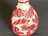a small red and white glass bottle on a table