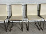 quatre chaises de salle à manger en cuir couleur crème avec des pieds chromés, dans un garage