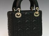 a close up of a black handbag on a white surface
