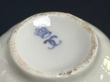 a close up of a white vase with a blue flower on it
