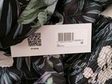 a label on a black and green floral print shirt