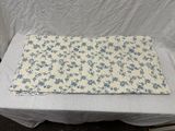 nappe à motifs floraux bleus et blancs posée sur une nappe blanche