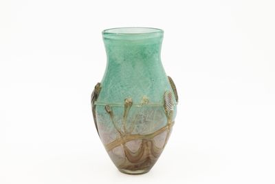 un vase vert posé sur une surface blanche