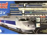 circuit de trains miniatures représentant un train argenté et bleu dans une gare