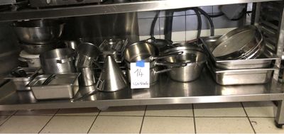 de nombreuses casseroles et poêles posées sur une étagère en acier inoxydable