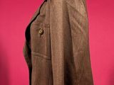 brown jacket on a mannequin stand against a red background