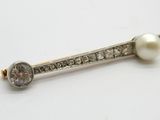 une image représentant une broche en forme de barre, ornée de diamants et de perles, posée sur un fond blanc