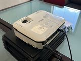 un ordinateur portable posé sur une pile de livres, sur une table en verre