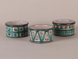 three green and white cups with designs on them on a gray surface