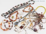many different types of necklaces and bracelets on the table