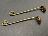 two antique brass spoons on a table next to each other
