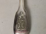 silver plated spoon with a design on it on a white surface