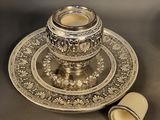 a silver plate with a candle on it next to a candle holder