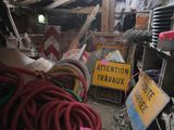 a pile of junk in a garage with a sign and hoses