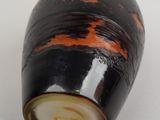 a black and orange vase sitting on a white surface