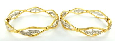 deux boucles d'oreilles pendantes en or et diamants blancs posées sur un fond blanc
