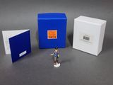 une petite figurine représentant un homme debout devant une cabine téléphonique bleue