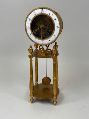 une horloge dorée avec un cadran blanc, posée sur un socle