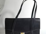 a black leather handbag with a gold buckle on the front