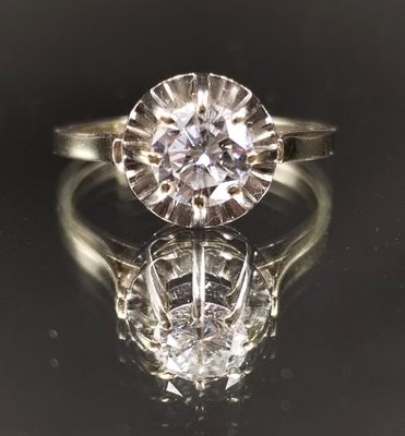a close up of a diamond ring on a reflective surface