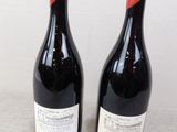 two bottles of wine sitting on top of a table next to each other