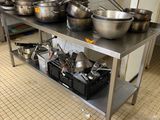 de nombreuses casseroles et poêles posées sur une table dans la cuisine