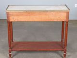 an old wooden table with a marble top on a concrete floor