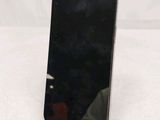 a black cell phone sitting on a stand on a white surface
