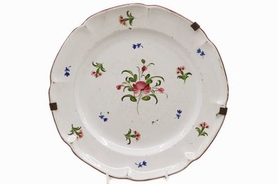 EST Assiette en faïence émaillée polychrome à décor floral.