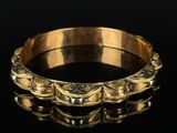 a close up of a gold bracelet on a black surface