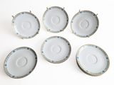 six white and blue china cups and saucers on a white surface