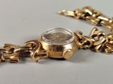 a close up of a gold watch with a chain around it